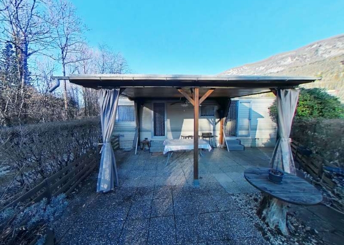 Vue extérieure du mobil-home Brookwood 2000, avec terrasse couverte et fermée, en location au camping en Savoie le Clairet